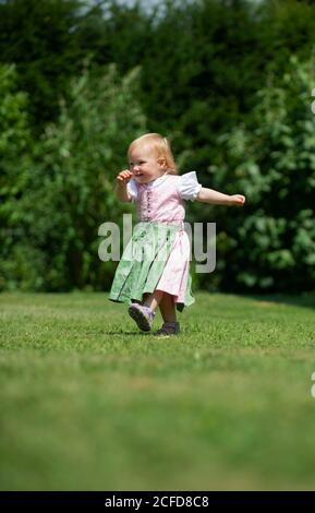 Mädchen in Dirndl läuft über eine Wiese, Oberbayern, Bayern, Deutschland Stockfoto