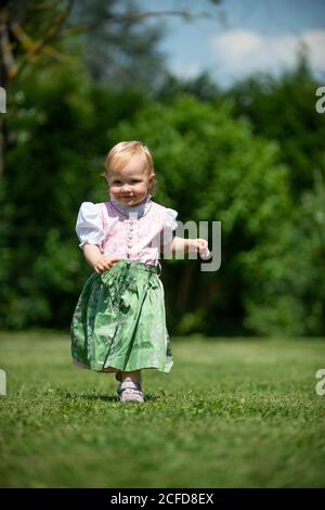 Mädchen in Dirndl läuft über eine Wiese, Oberbayern, Bayern, Deutschland Stockfoto