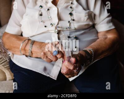 Elegant gealterte weibliche Einnahme Pillen sitzen auf Sessel zu Hause Stockfoto