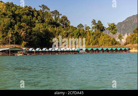 Blick über eine Fußgängerbrücke mit Bungalows (Khao Sok Smiley Lake House) auf das Wasser des Ratchaprapha Sees im Khao Sok Nationalpark, Khao Sok, Thailand Stockfoto