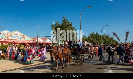 Straße mit Casetas, traditionell gekleidete Besucher und Pferdekutsche, Feria de Abril, Sevilla, Andalusien, Spanien Stockfoto