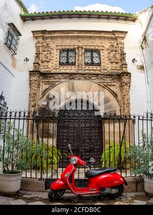 Roter Roller Piaggio Vespa vor einer Eingangstür, Santa Cruz, Sevilla, Andalusien, Spanien Stockfoto