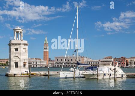 Blick über Bacino di San Marco nach Venedig mit Campanile di San Marco und Dogenpalast, vor Leuchtturm und Booten, Venedig, Italien Stockfoto