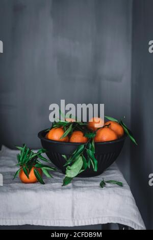 Orange Mandarinen in Keramik Zierschale auf Tisch Stockfoto