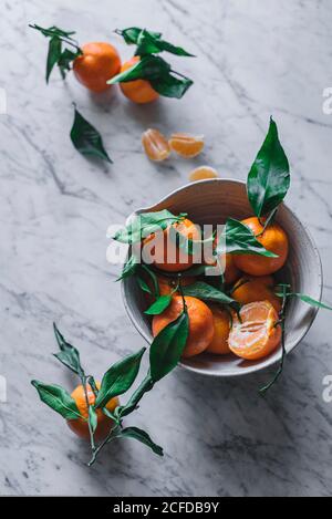 Orange Mandarinen in Keramik Zierschale auf Marmortisch Stockfoto