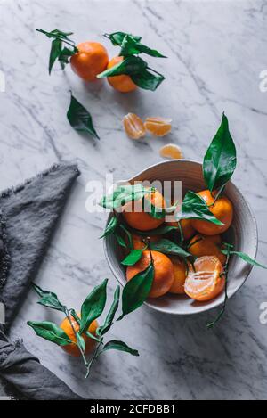 Orange Mandarinen in Keramik Zierschale auf Marmortisch Stockfoto