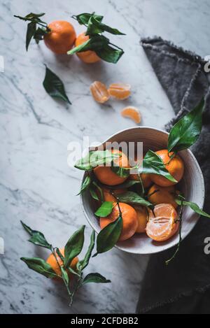 Orange Mandarinen in Keramik Zierschale auf Marmortisch Stockfoto