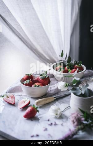 Erdbeeren und Blumen auf Marmortisch Stockfoto