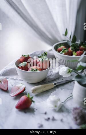 Erdbeeren und Blumen auf Marmortisch Stockfoto