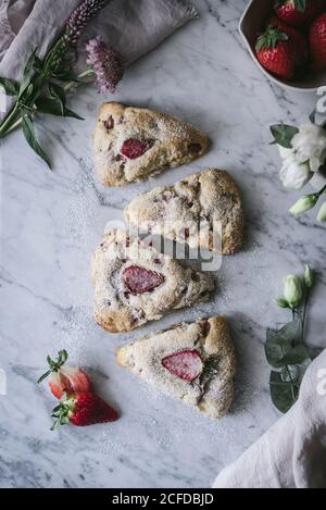 Set von köstlichen Erdbeer Scones auf weißem Marmor Tischplatte platziert In der Nähe von Blumen Stockfoto