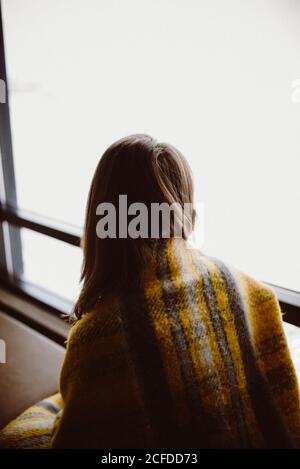 Frau sitzt am Fenster und schaut auf die verschneite Isländische Landschaft Stockfoto