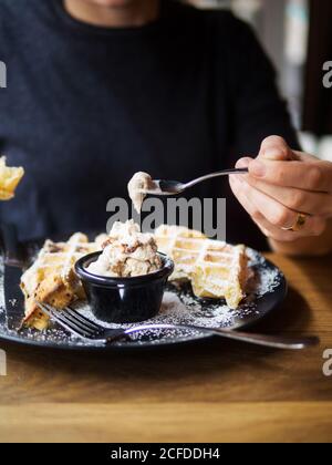 Unkenntliche Person, die kaltes, süßes Eis und frische Waffeln genießt Während des Mittagessens im Café Stockfoto