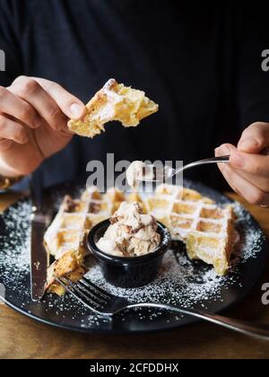 Unkenntliche Person, die kaltes, süßes Eis und frische Waffeln genießt Während des Mittagessens im Café Stockfoto