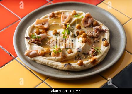 Von oben leckere appetitliche Pizza mit Schinken und Kichererbsen in Scheiben Mit ihr auf grauem Teller bestreut Stockfoto