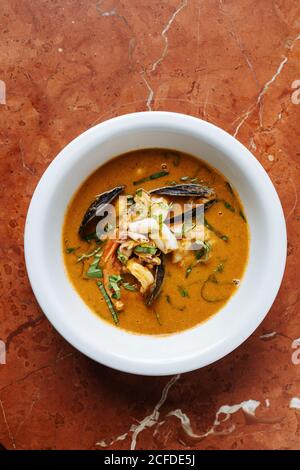 Von oben Nahaufnahme Ragout mit Fischmuscheln gekocht kleinen Tintenfisch Und Kräuter auf dem Teller im Restaurant Stockfoto