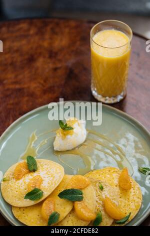 Von oben Teller mit Pfannkuchen mit Scheiben verziert Mandarine Blätter der Minze mit Sauce und Glas serviert Orangensaft Stockfoto