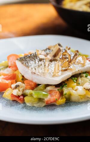 Von oben von Filetfisch mit kleinen quadratischen Scheiben Paprika auf dem Teller im Restaurant Stockfoto
