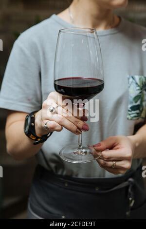 Von unten der Ernte unkenntlich weibliche Hand mit stilvollen Glas Von Rotwein Stockfoto