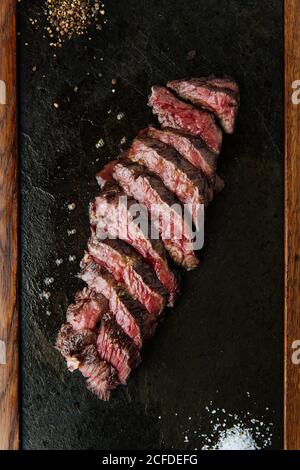 Draufsicht auf mittelseltene Scheiben Steak auf dem Tisch mit Gabel und Messer im Restaurant Stockfoto