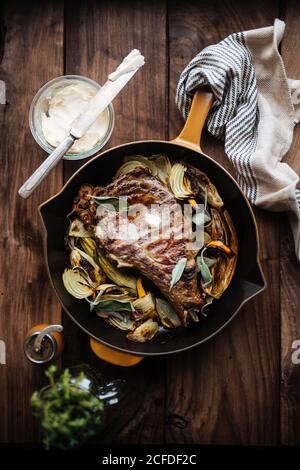 Blick von oben auf aromatisch schmackhaftes gegrilltes Fleischsteak mit Zwiebeln Und Kräuter mit Butter in der Pfanne auf Holz serviert Tabelle Stockfoto