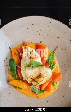 Blick von oben auf Haute Cuisine Restaurant Gericht mit gegrilltem gemacht Fisch und Eintopf Gemüse garniert mit frischem Spinat Stockfoto