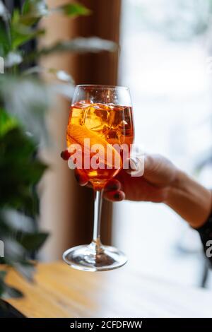 Anonyme Frau mit Alkoholcocktail mit aperol und Campari, dekoriert mit Orangenscheiben im Restaurant Stockfoto