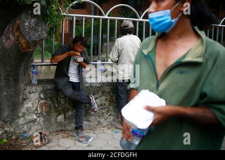 Lalitpur, Nepal. September 2020. Tägliche Wetten und Obdachlose essen kostenlose warme Mahlzeiten während der Coronavirus-Sperre, um die Ausbreitung von COVID-19 in Mahalaxmisthan in Lalitpur, Nepal am Samstag, 5. September 2020 einzudämmen. Die Hiteri-Stiftung, in der die Werke von Kusum Tamang Poudyal mehr als 2500 warme Mahlzeiten während der ersten Sperre verteilt haben, sowie Lebensmittelverpackungen im Wert von einem Monat an mehr als 2200 Familien in der Krise. Während der zweiten Sperre verteilten sie bereits rund 900 Mahlzeiten und rund 20 Lebensmittelverpackungen an Familien in der Krise, wobei etwa 65 Familien darauf warteten, diese Pakete zu erhalten. Kusum heute pro Stockfoto