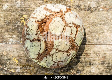 Runder, frisch gebackener Laib Brot von oben, verwitterter Holzhintergrund Stockfoto