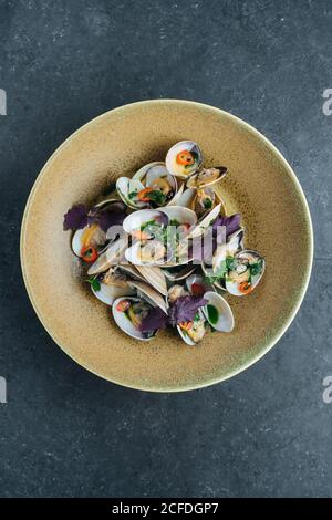 Von oben schmackhafte Muscheln mit geschnittenem Chili und serviert Frische Basilikumblätter auf dem Teller im Restaurant Stockfoto