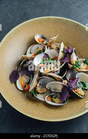 Von oben schmackhafte Muscheln mit geschnittenem Chili und serviert Frische Basilikumblätter auf dem Teller im Restaurant Stockfoto