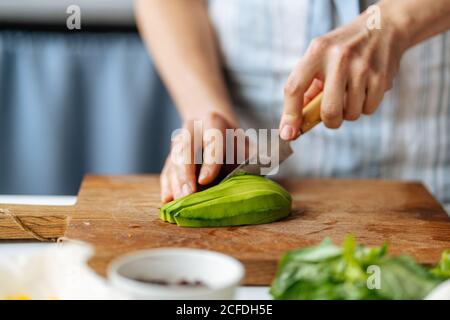 Frau schneidet Avocado auf Schneidebrett Stockfoto