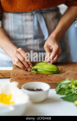 Frau schneidet Avocado auf Schneidebrett Stockfoto