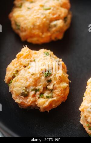 Nahaufnahme von gesundem fleischlosen, ungekochten Orangenlachs und Gemüseschnitzel Oder Burger auf schwarzer Oberfläche Stockfoto