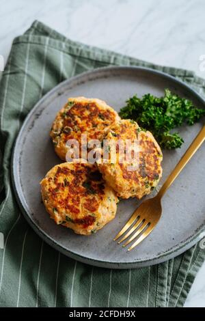 Gesunde leckere gegrillte Koteletts aus Fisch und Gemüse serviert Auf Metallplatte mit Gabel und mit Brokkoli garniert Stockfoto