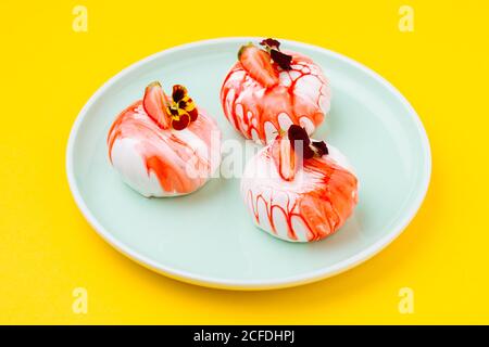 Von oben schmackhafte Desserts mit frischen Erdbeeren und Blumen platziert Auf Platte auf gelbem Hintergrund Stockfoto