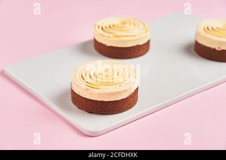 Closeup köstliche Schokoladengebäck mit Sahne Spirale dekoriert und platziert An Bord auf rosa Hintergrund Stockfoto