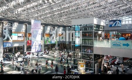 Sapporo, Hokkaido, Japan - überfüllte Touristen am Inlandsterminal Atrium des New Chitose Flughafens. Werbung hängende Banner über Nippon-Ham Fighters. Stockfoto