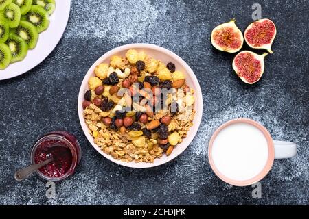 Gesundes Frühstückszerealien, Müsli mit Rosinen und Nüssen. Eine Schüssel mit trockenem Müsli mit Milch auf dunklem Grund. Snack-Lebensmittel von Haferflocken. Stillleben. F Stockfoto