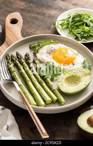 Gesundes hausgemachtes Frühstück mit Spargel, Spiegelei, Avocado und Rucola. Quarantäne gesundes Essen Konzept. keto Diät Stockfoto