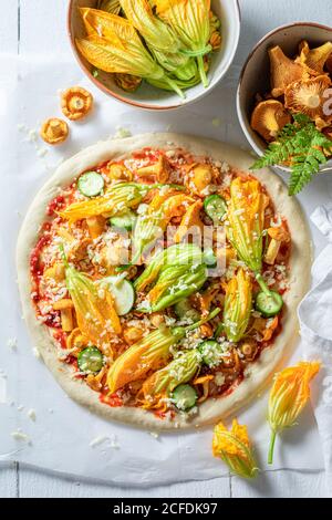 Zutaten für hausgemachte Pizza mit Pfifferlingen, Zucchini und Mozzarella auf Backpapier Stockfoto