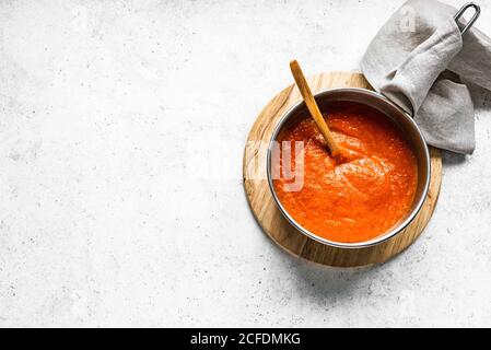 Hausgemachte Tomatensauce in der Pfanne auf weißem Tisch, Draufsicht, Kopierplatz. Herstellung von Bio-italienische Tomatensauce oder Suppe. Stockfoto