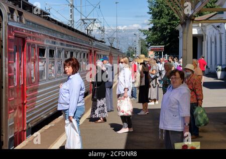 Sankt Petersburg, Russland - 08. August 2020: Menschen stehen auf dem Bahnsteig zur Zeit des covid-19 vor dem Elektrozug, einige von ihnen in Sanitäter Stockfoto