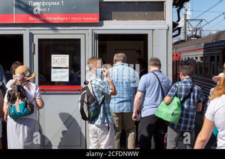 Sankt Petersburg, Russland - 08. August 2020: Ankommende Passagiere aus dem Zug betreten das Bahnhofsgebäude der Reihe nach. Der maskierte junge Mann sah sich um. Stockfoto