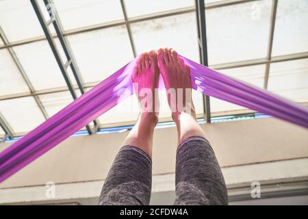 Von unten barfuß weiblich in Sport Leggings dehnt Muskeln Mit Widerstandsband beim Training im Fitnessstudio Stockfoto