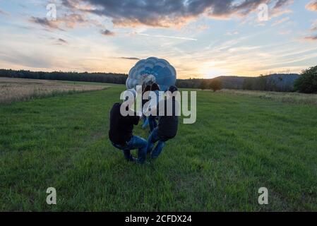 Deutschland, Thüringen, Ellrich, vier Menschen ziehen an einem Heißluftballon. Stockfoto