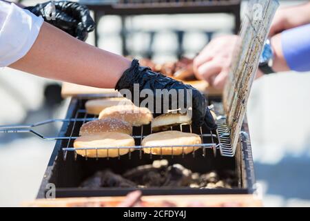 Der Küchenchef bereitet gegrillte Hamburger-Brötchen zu.Grillfleisch. Ein Stück Fleisch im Rauch. Stockfoto