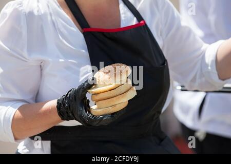 Hamburger Brötchen in den Händen des Küchenchefs. Stockfoto