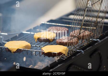 Hamburger Patties mit Käse werden gegrillt.gegrilltes Fleisch. Ein Stück Fleisch im Rauch. Stockfoto