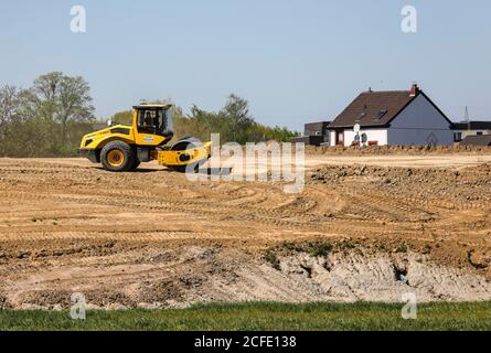 Eine Straßenwalze verdichtet den Damm über dem hoch gelegenen Kanal im Baufeld, Häuser dahinter, Kanalneubau Emscher, Emscher Stockfoto