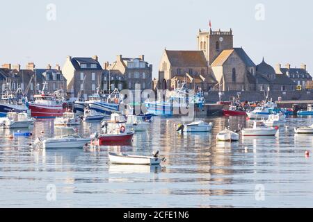 Boote im Hafen von Barfleur, dahinter die Kirche des Hl. Nikolaus. Die Stadt ist einer der schönsten Orte in Frankreich. Stockfoto